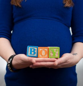 pregnant woman holding blocks that spell out "Boy"